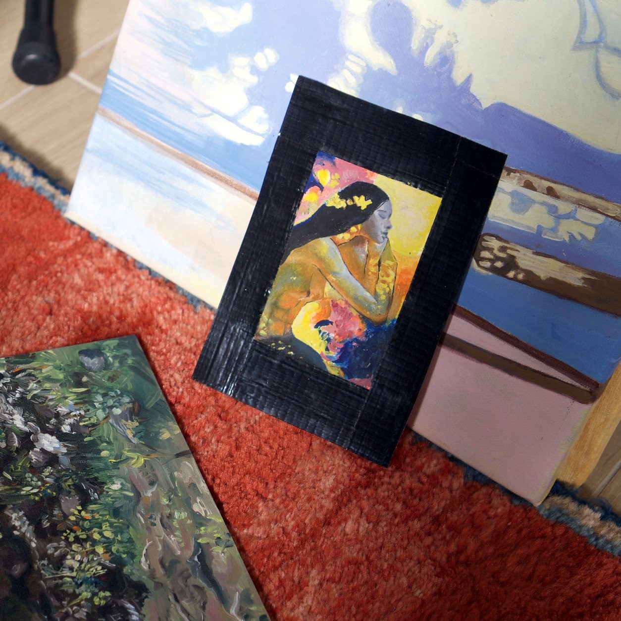 Golden Muse in its black mount, propped up on a rug among other paintings